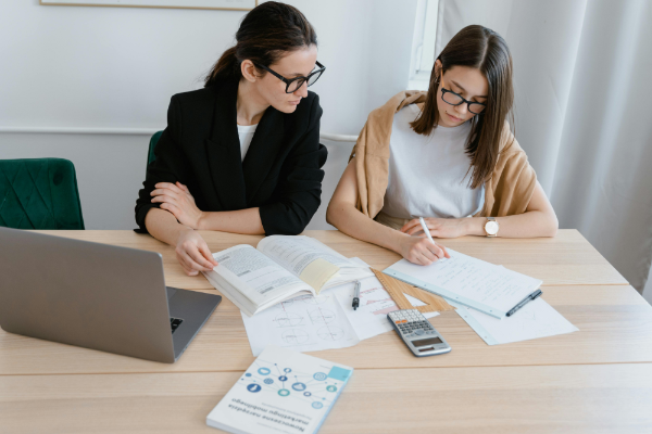 A businesswoman and her tutor sit together at a desk