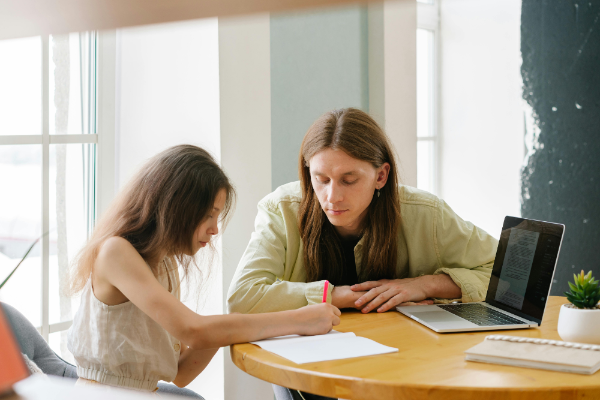 A teacher and young student sit together at a desk